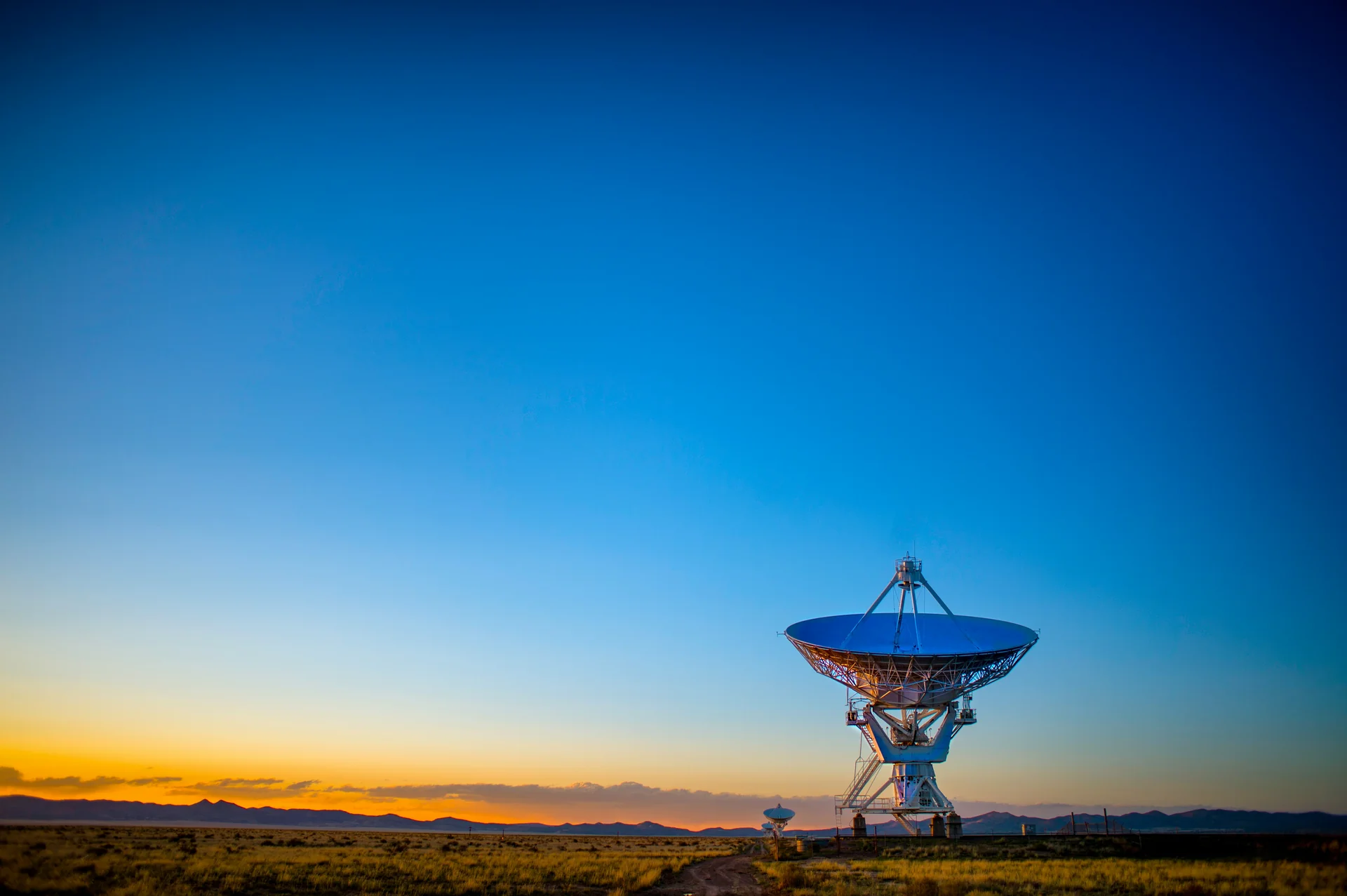 Radiotelescopio en una llanura abierta al atardecer.